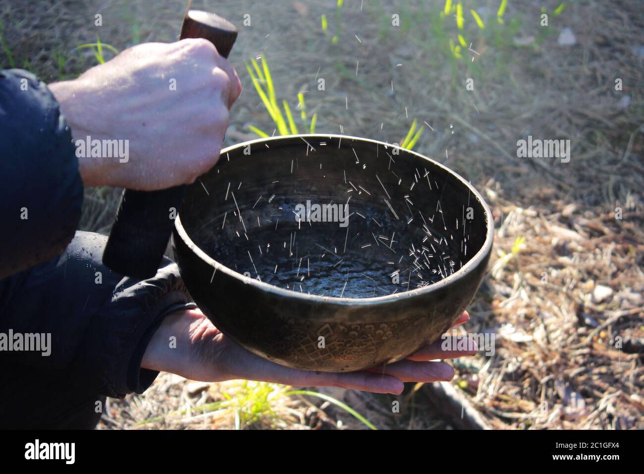 Tibetan bowl with dancing like boiling water in the sunlight in nature as a result of playing on it Stock Photo