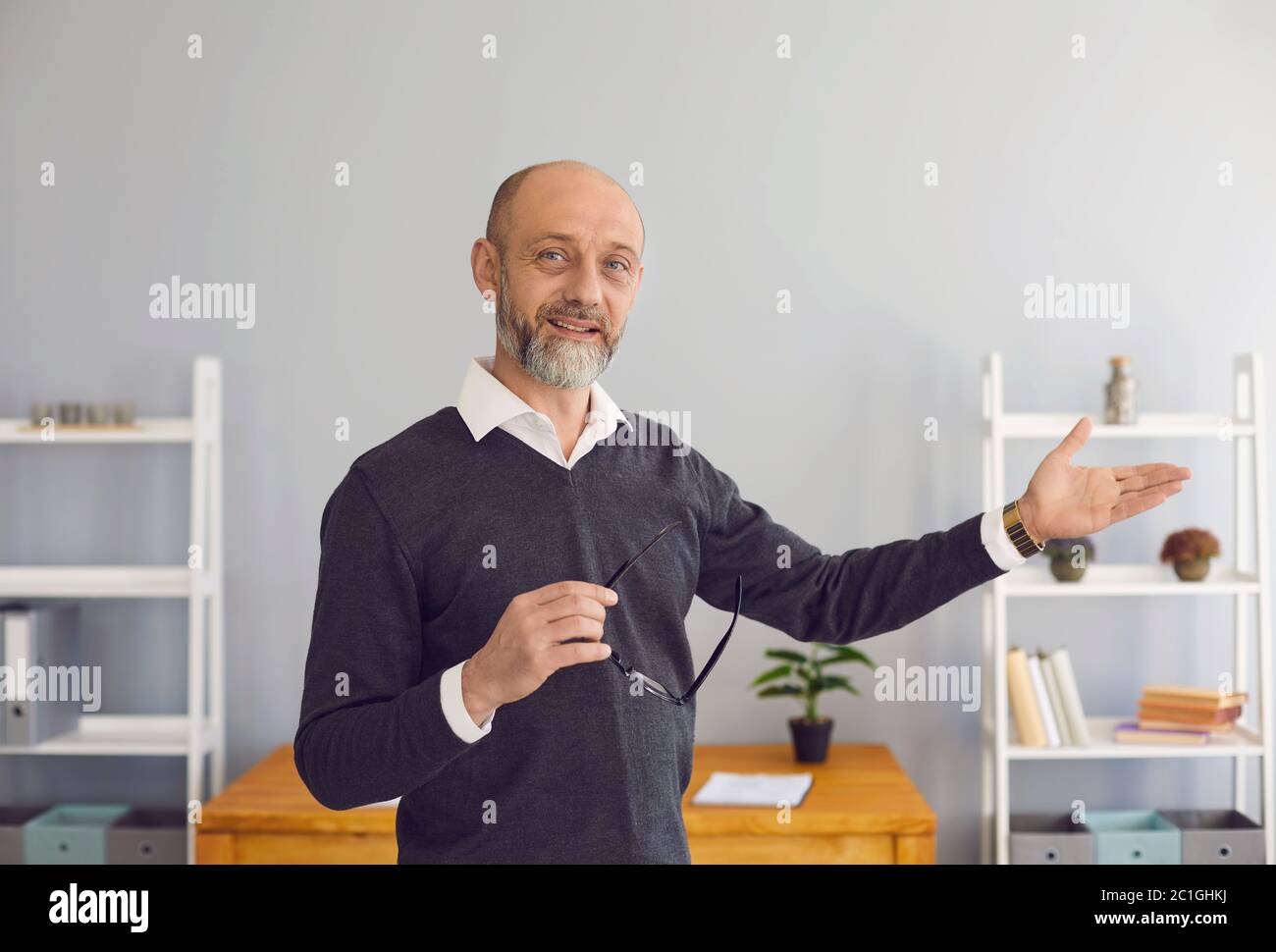 A middle-aged male professor looking at the camera uses web chat, says a business strategy remotely in a room at home. Stock Photo