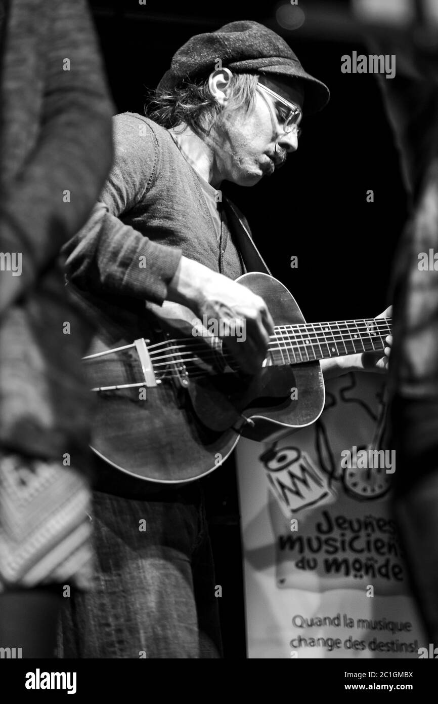 Guitarist teacher playing guitar with children at a show of Jeunes Musiciens du Monde. Stock Photo