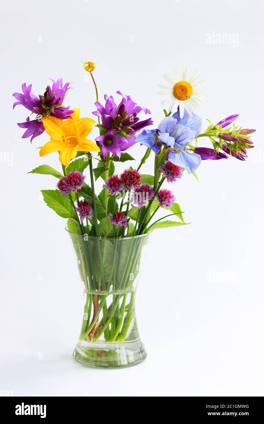 a bouquet of different wild field and garden flowers: chamomile, bell, lily, chives, iris. Stock Photo