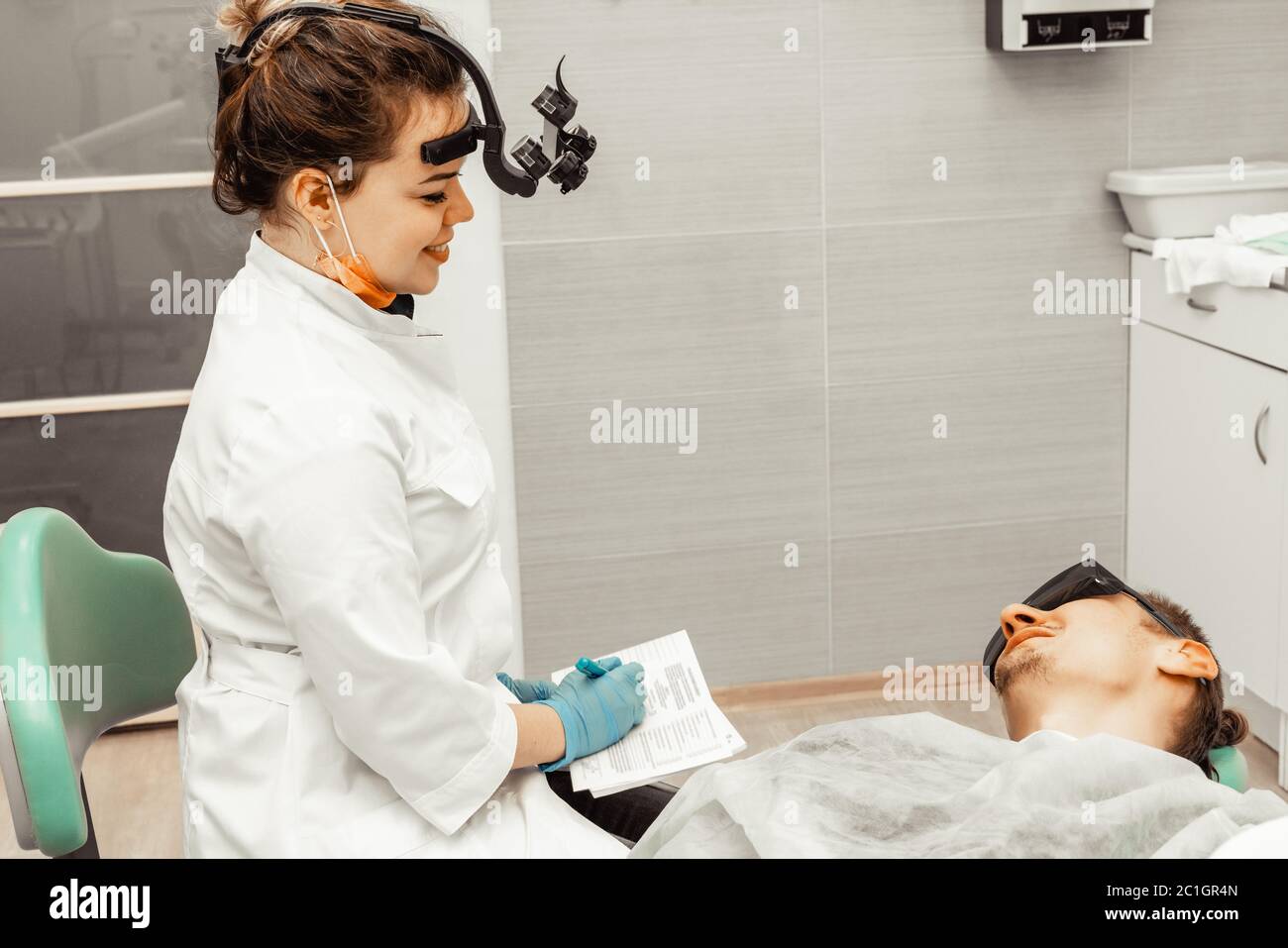Young woman dentist doctor at the workplace conducts a patient survey. History taking