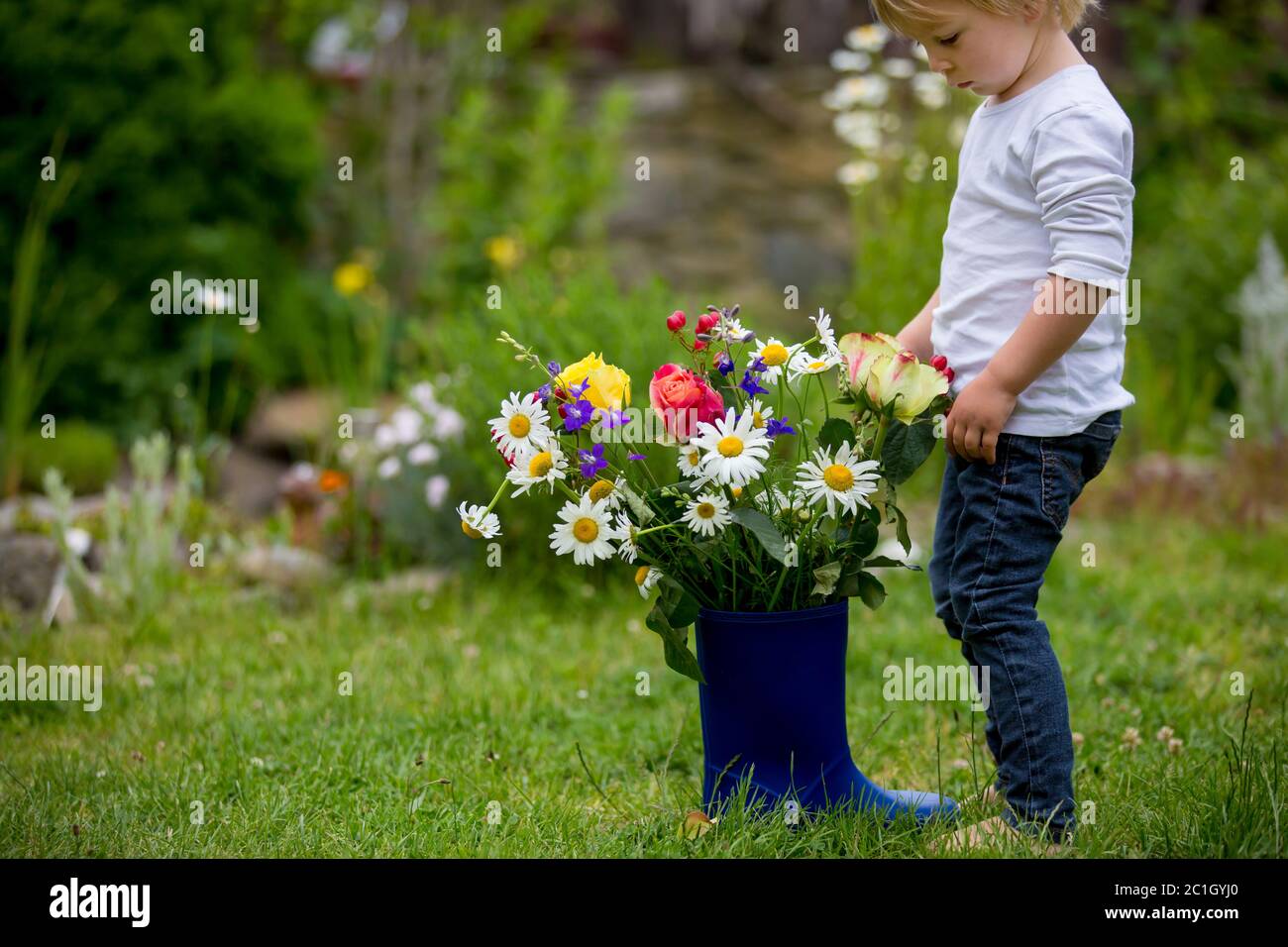 Child holding rubber boots with beautiful flowers in garden Stock Photo ...