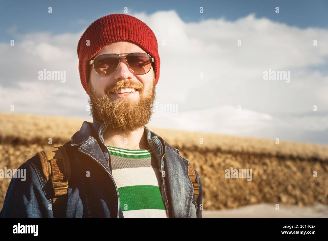 Portrait of a young hipster man wearing sunglasses and a hat. A smiling bearded man wearing sunglasses. Happy man with a beard Stock Photo