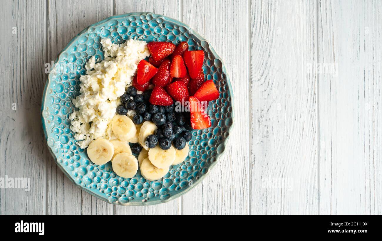 Healthy summer breakfast. Cottage cheese with strawberry blueberry banana and honey. Beautiful breakfast Stock Photo