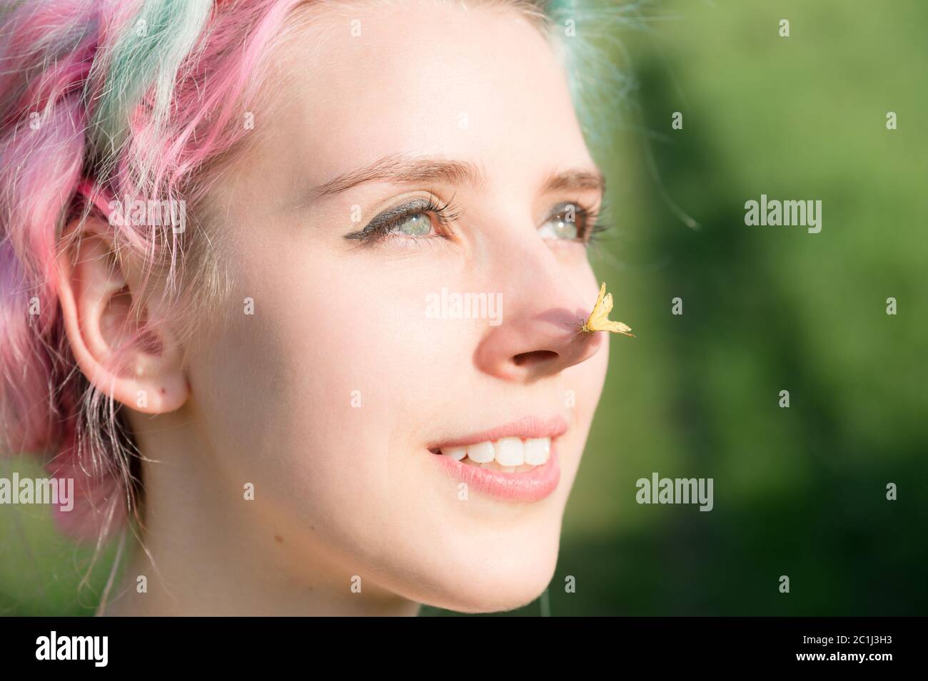 Yellow butterfly sitting on the nose Cute young girl on nature. Harmony and enjoyment in nature Stock Photo