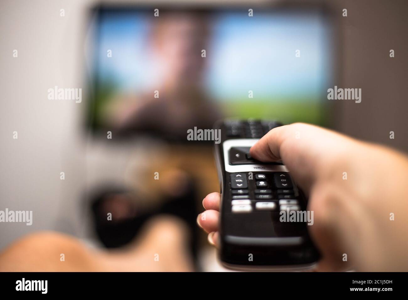 Hand Holding Use Remote Control and Watching TV in House on a colorful ...