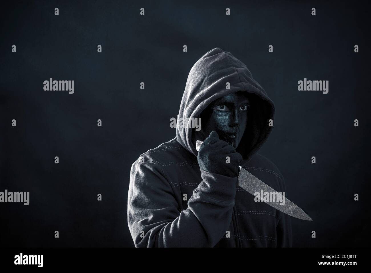 Hooded man with black mask holding knife in the dark Stock Photo Alamy