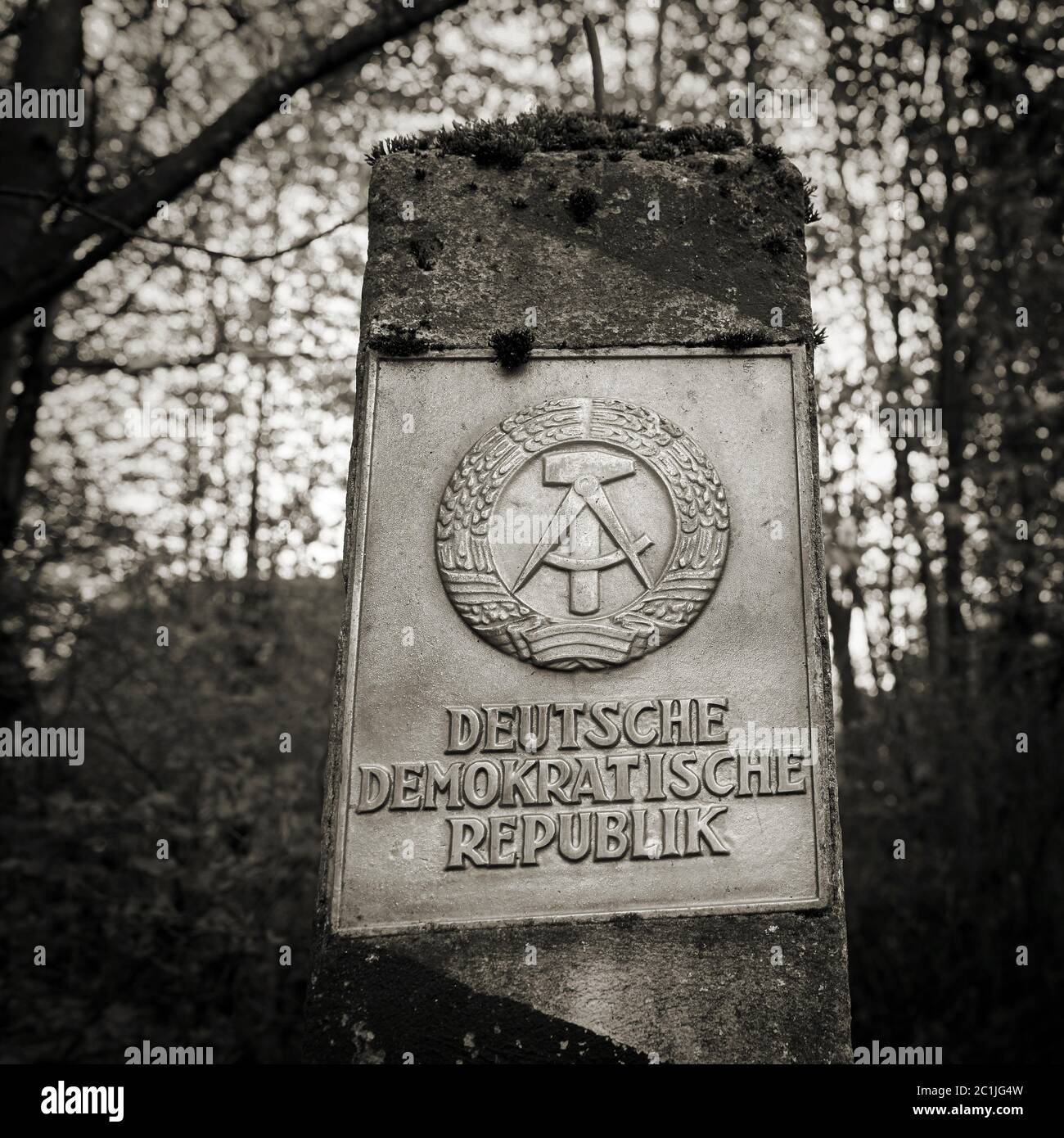 Border pillar of the former inner German border with the emblem of the GDR in the forest in the Harz National Park Stock Photo