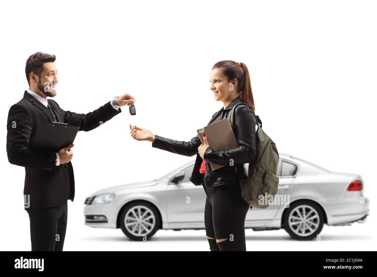 Car salesman giving car keys from a silver car to a young female student isolated on white background Stock Photo