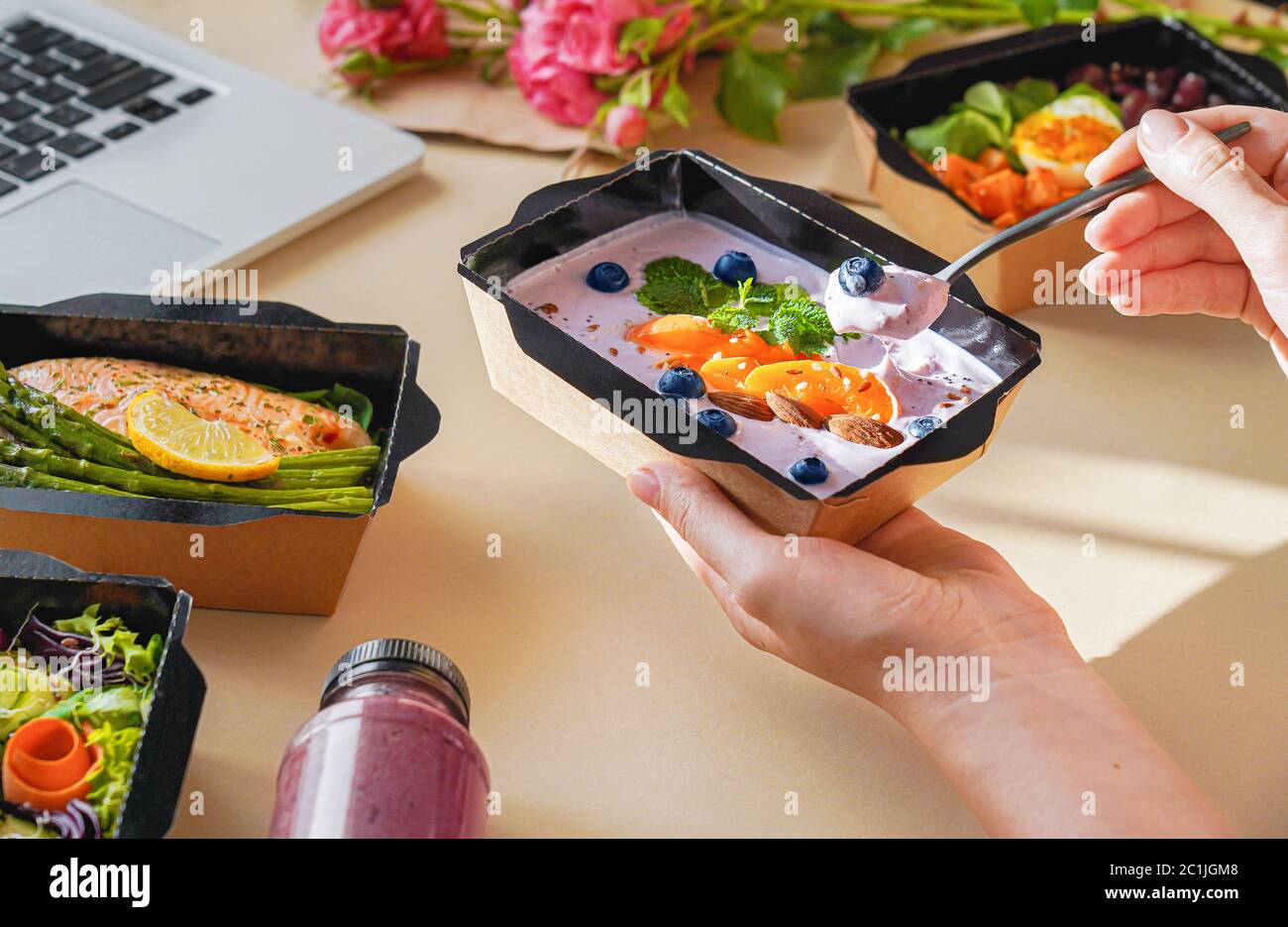 Woman holding lunch delivery box eating working from home office, close up. Stock Photo