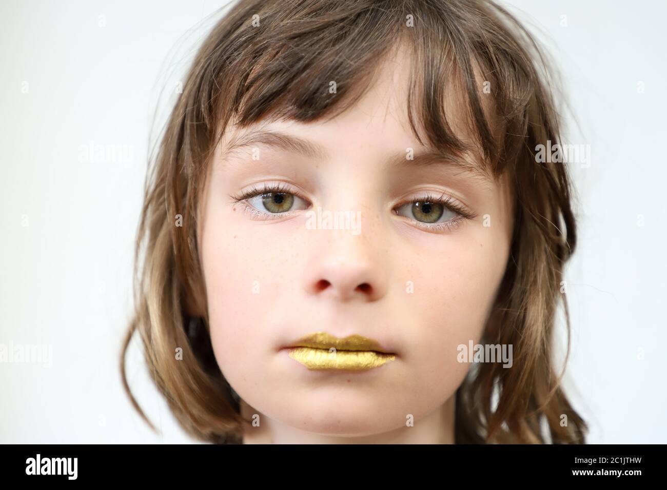 Portrait of a child with golden lips and a weary look Stock Photo