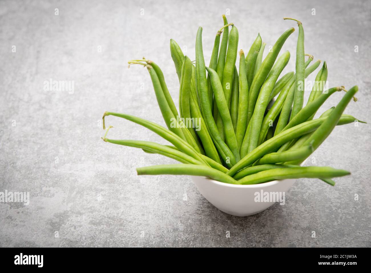 Fresh green string beans on a plate on grey structured background. Stock Photo