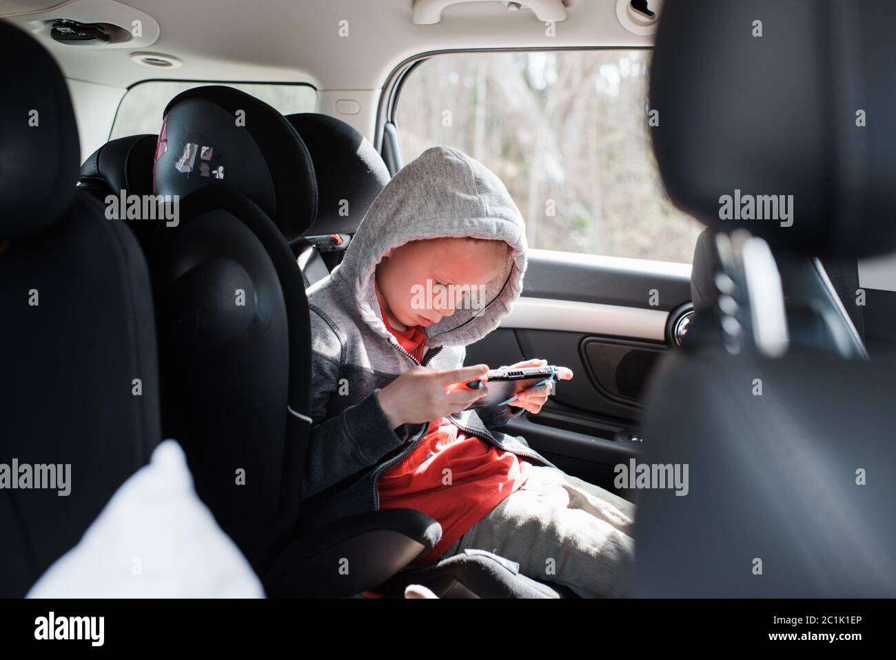 boy sat in his car seat playing a Nintendo video game console Stock Photo