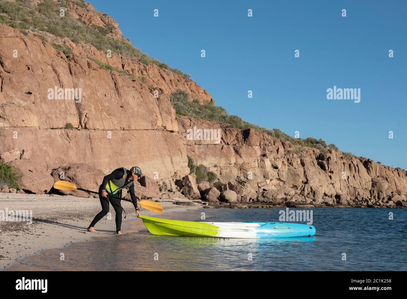 One woman wearing a wetsuit and holding a paddle getting ready to jump