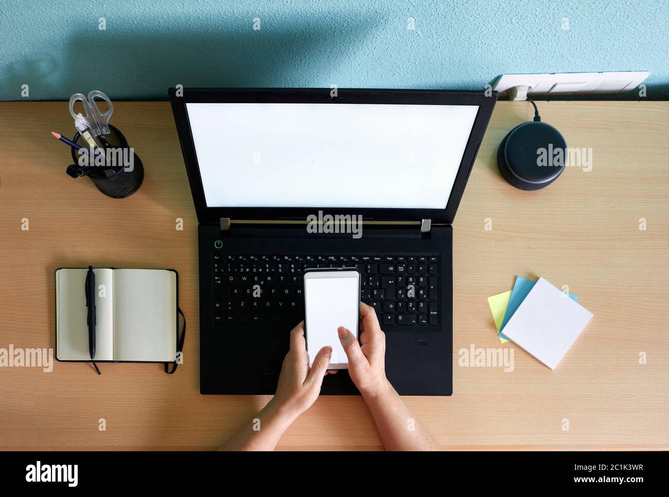 Unrecognizable woman writes on her smartphone at a desk in her home Stock Photo