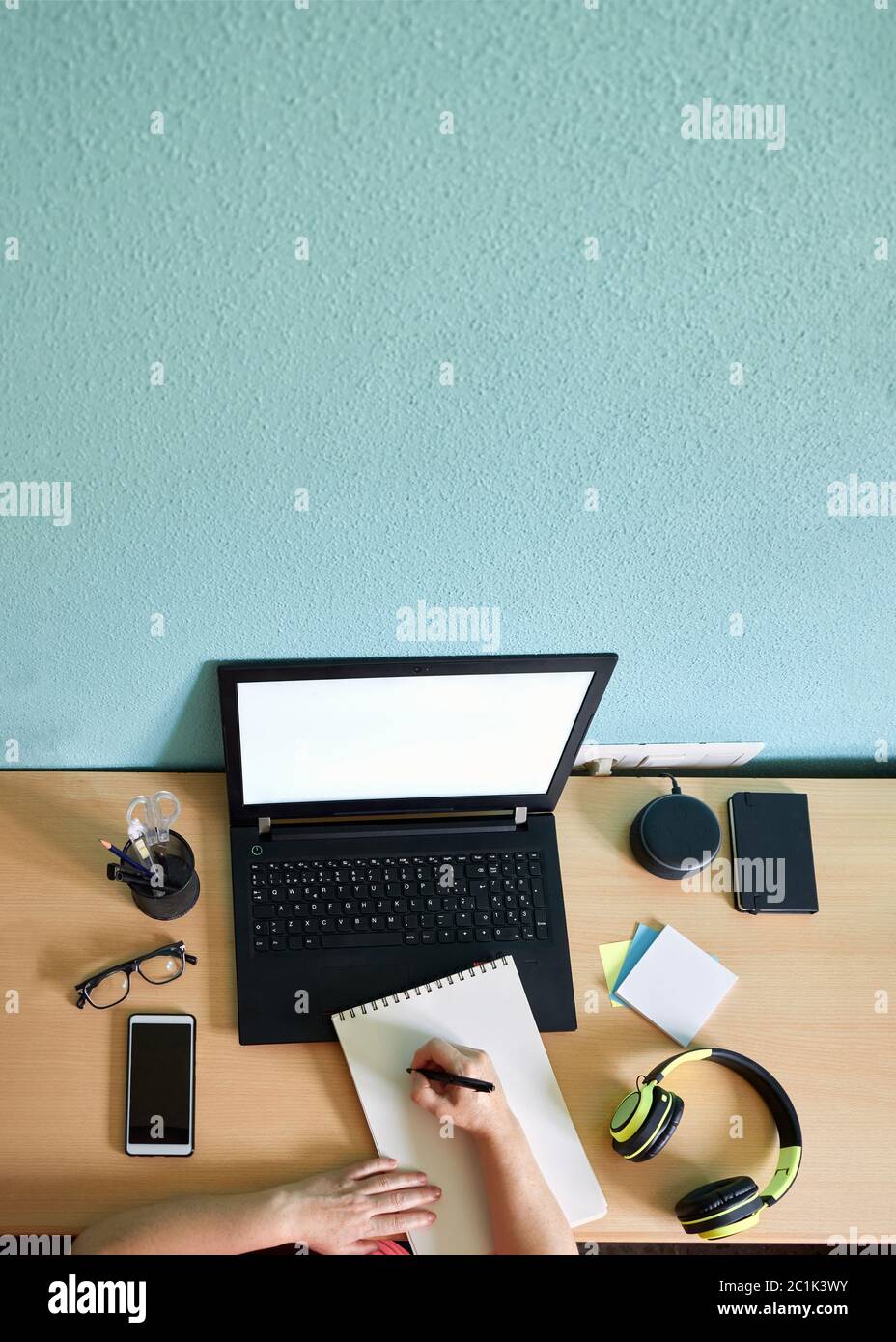 Unrecognizable woman writes on her notebook on a desk in her home Stock Photo