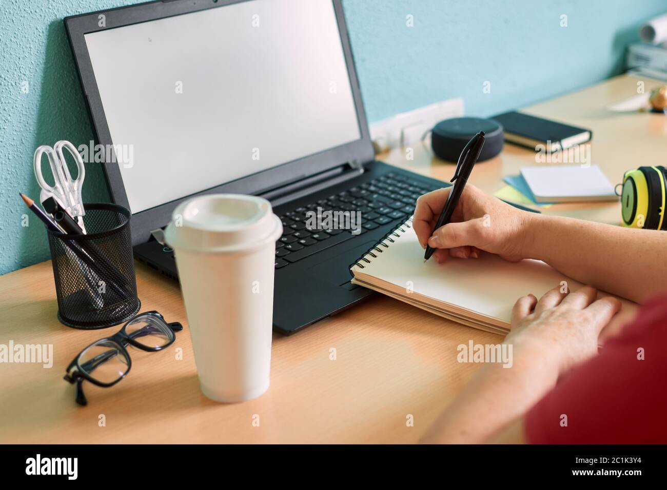 Unrecognizable woman writes on her notebook on a desk in her home Stock Photo