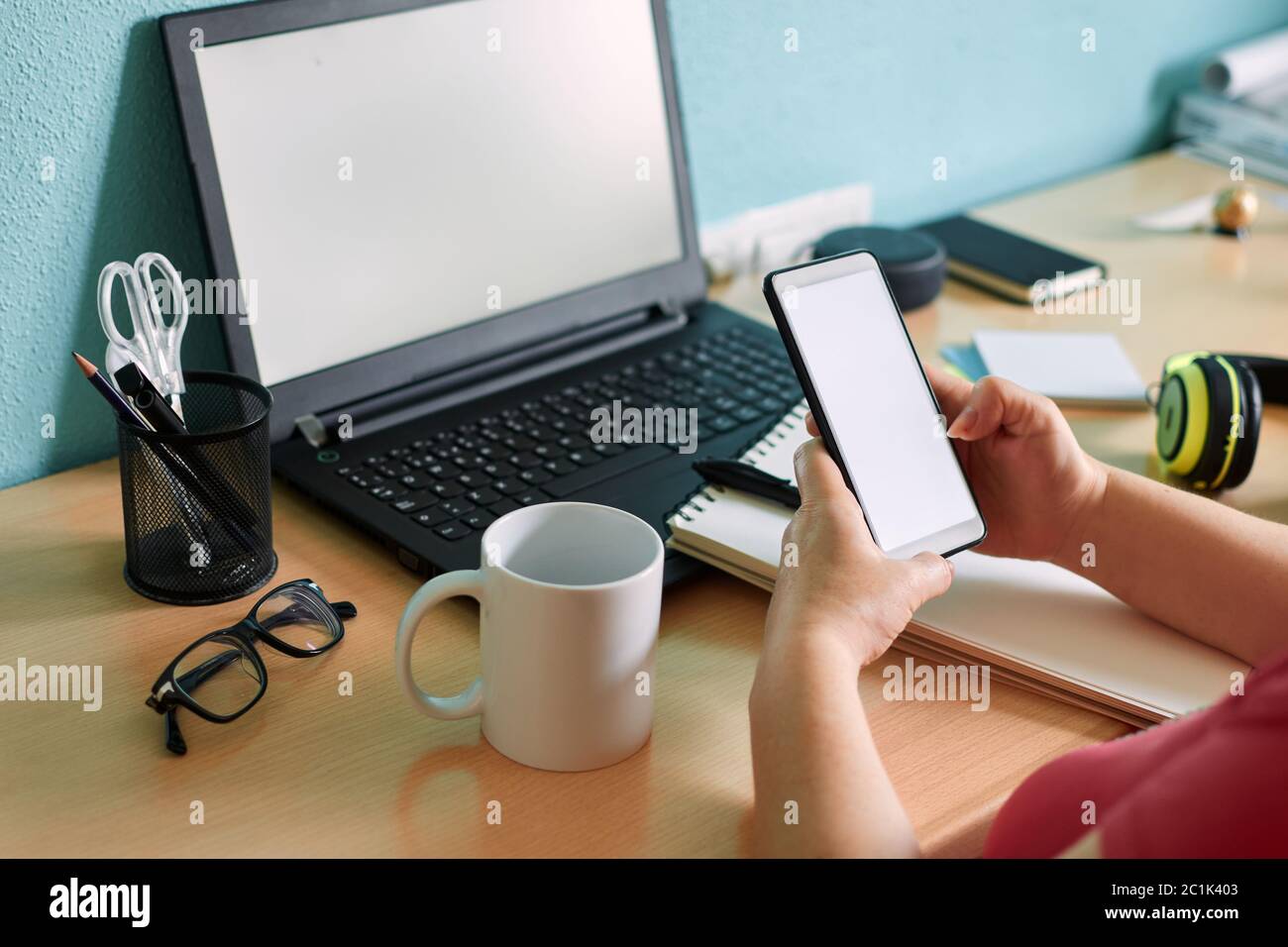 Unrecognizable woman writes on her smartphone at a desk in her home Stock Photo