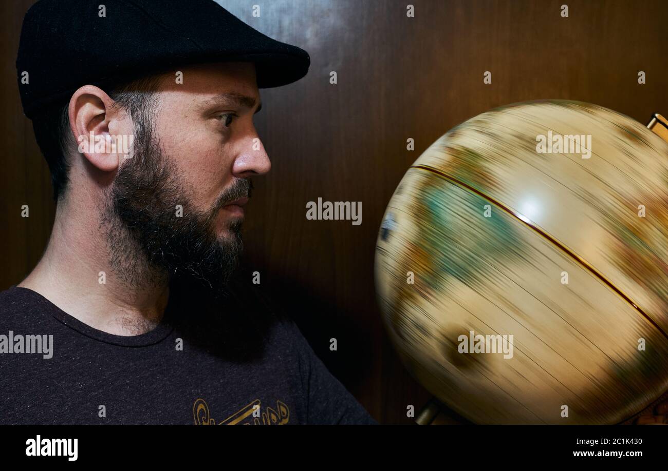 bearded man watching globe spinning Stock Photo