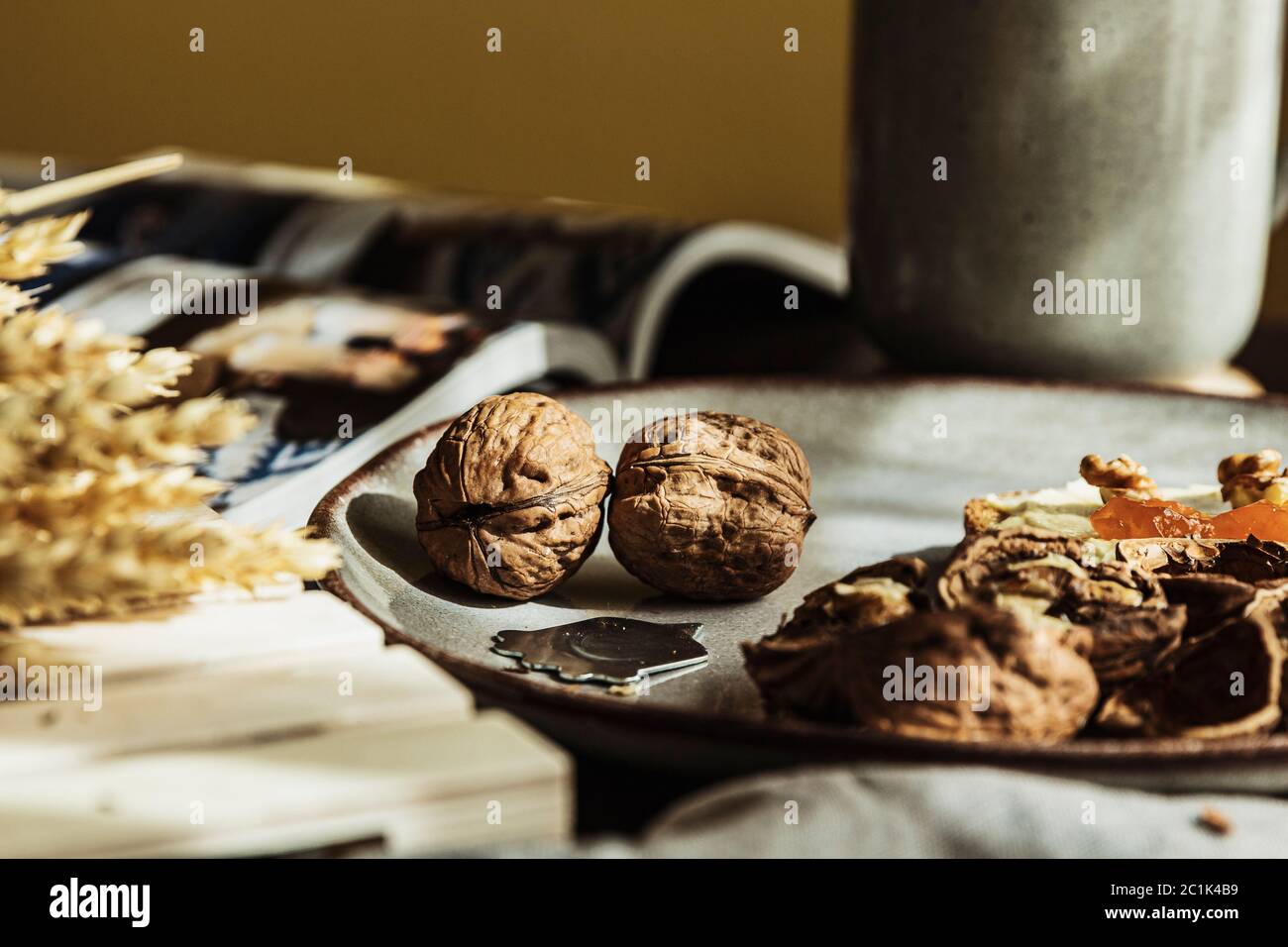 Still life of two beautiful walnuts nuts and a nutpick on a plate in a cozy wooden table for breakfast Stock Photo