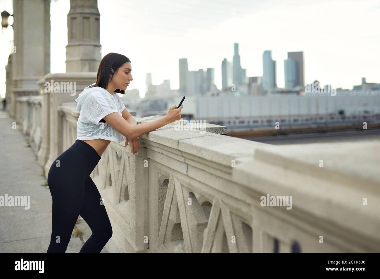 Woman using mobile phone leaning on bridge in city Stock Photo