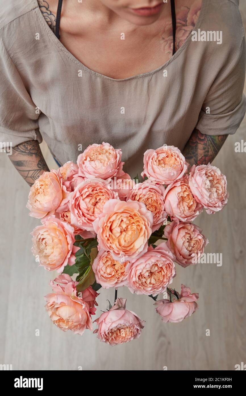 A tender bouquet of pink roses, a woman is holding in hands on a gray ...