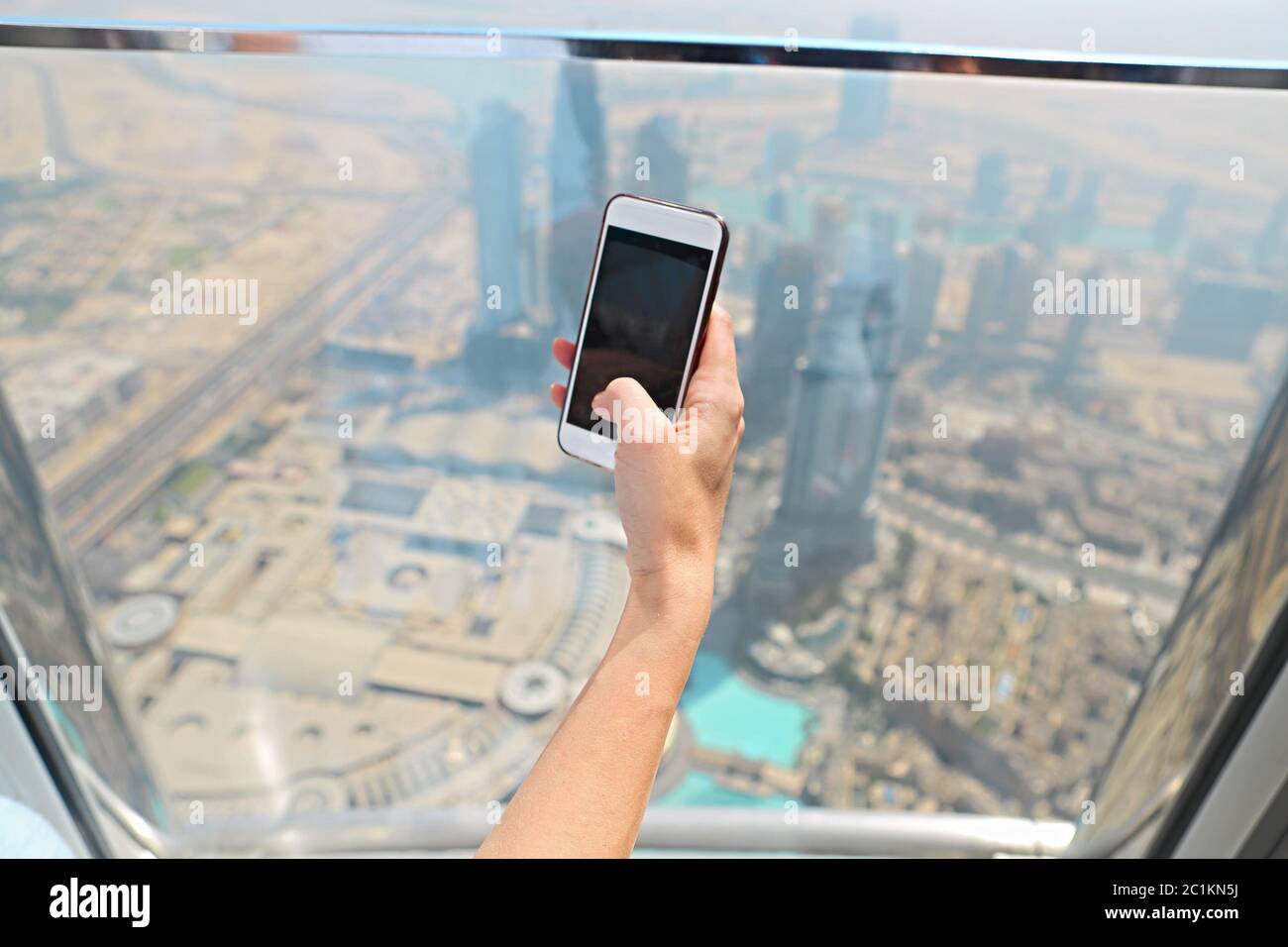 Girl tourist with mobile phone by the window of skyscraper of the Burj  Khalifa in Dubai Stock Photo - Alamy