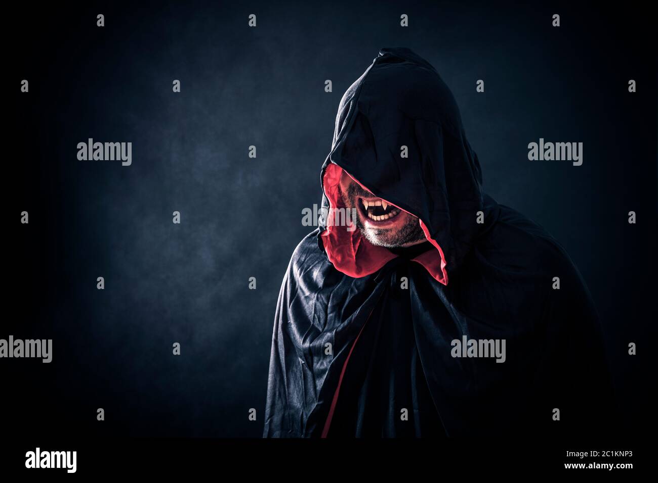 Angry vampire with red cape showing his scary teeth Stock Photo