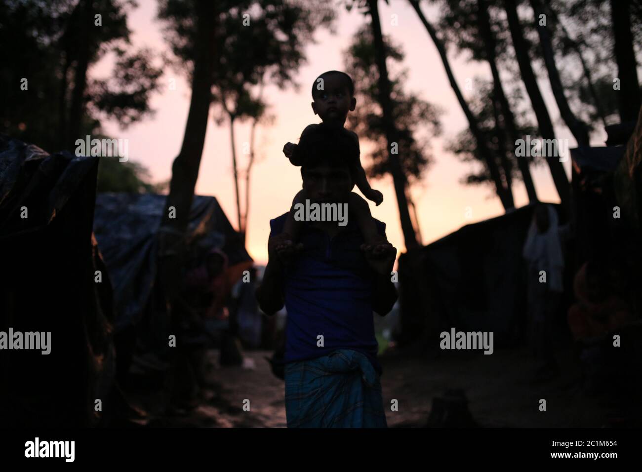 A Rohingya man walks carrying his child at Kutupalong refugee camp, Bangladesh, Tuesday, Oct. 03, 2017. Stock Photo