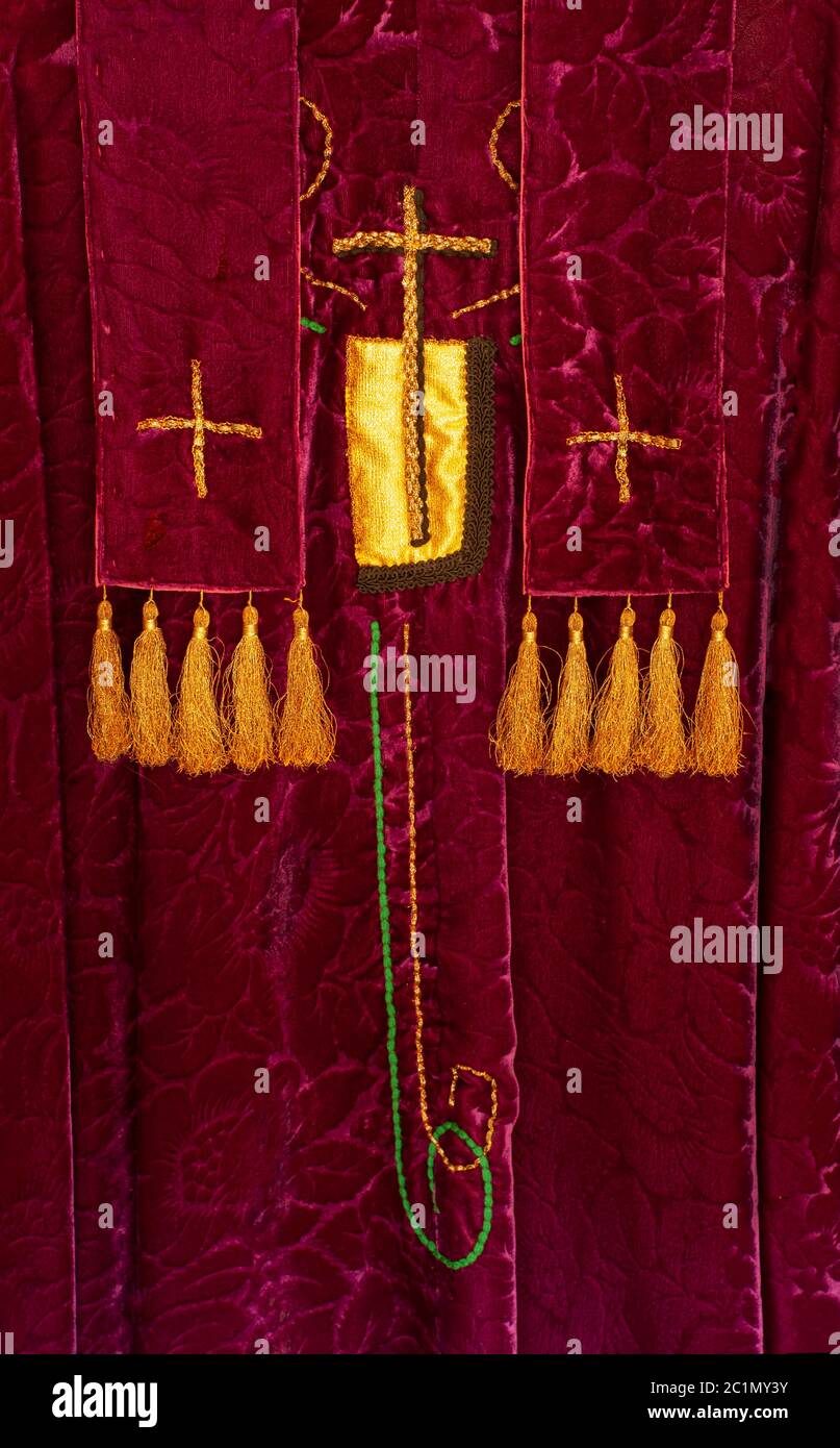 Priest's liturgical vestments. Purple velvet with gold crosses and tassels. Closeup shows symbols of Christian worship service on feast days. Stock Photo