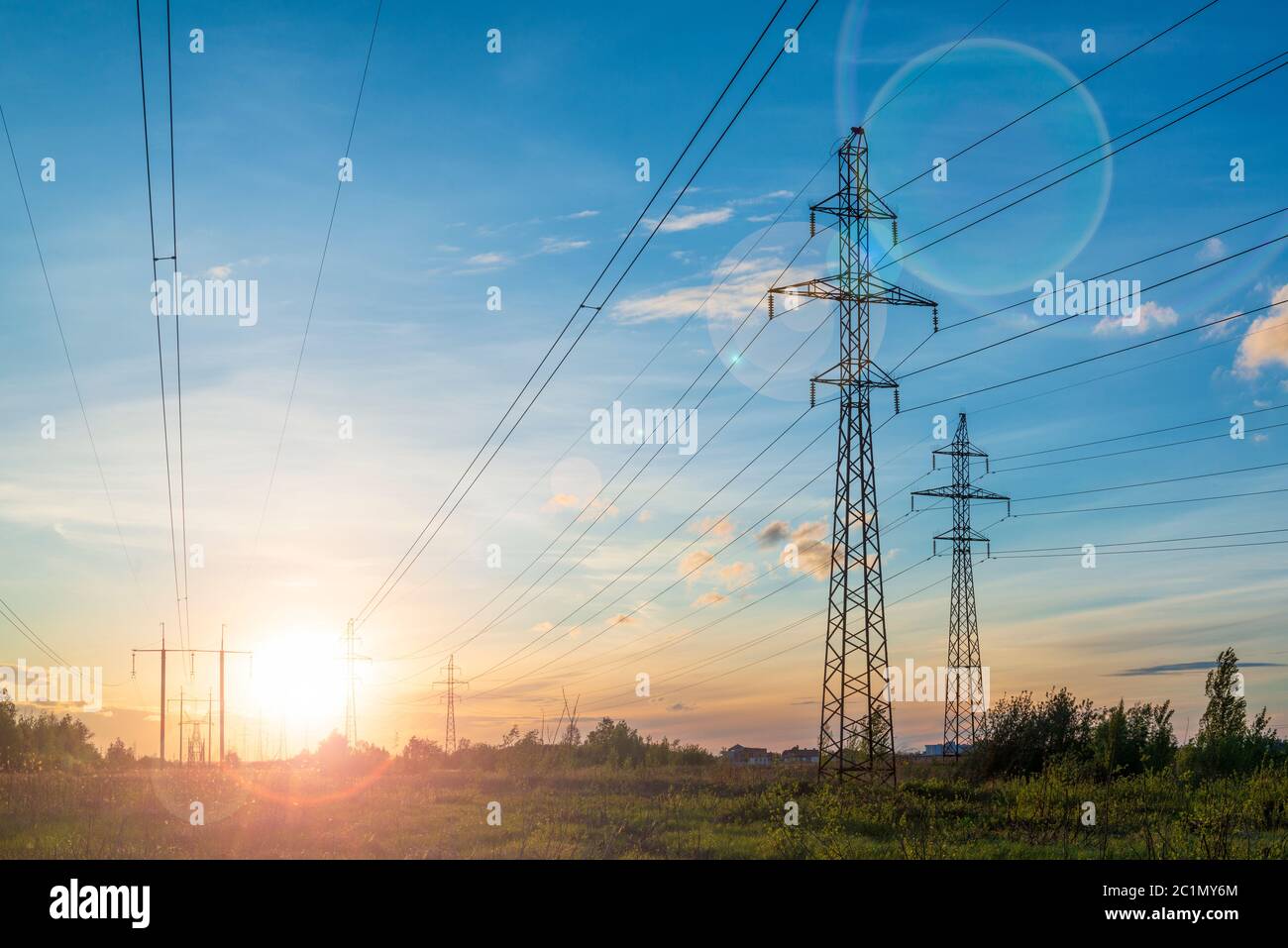 Multiple power lines at the sunset with sun flare. Energy distribution and environment Stock Photo