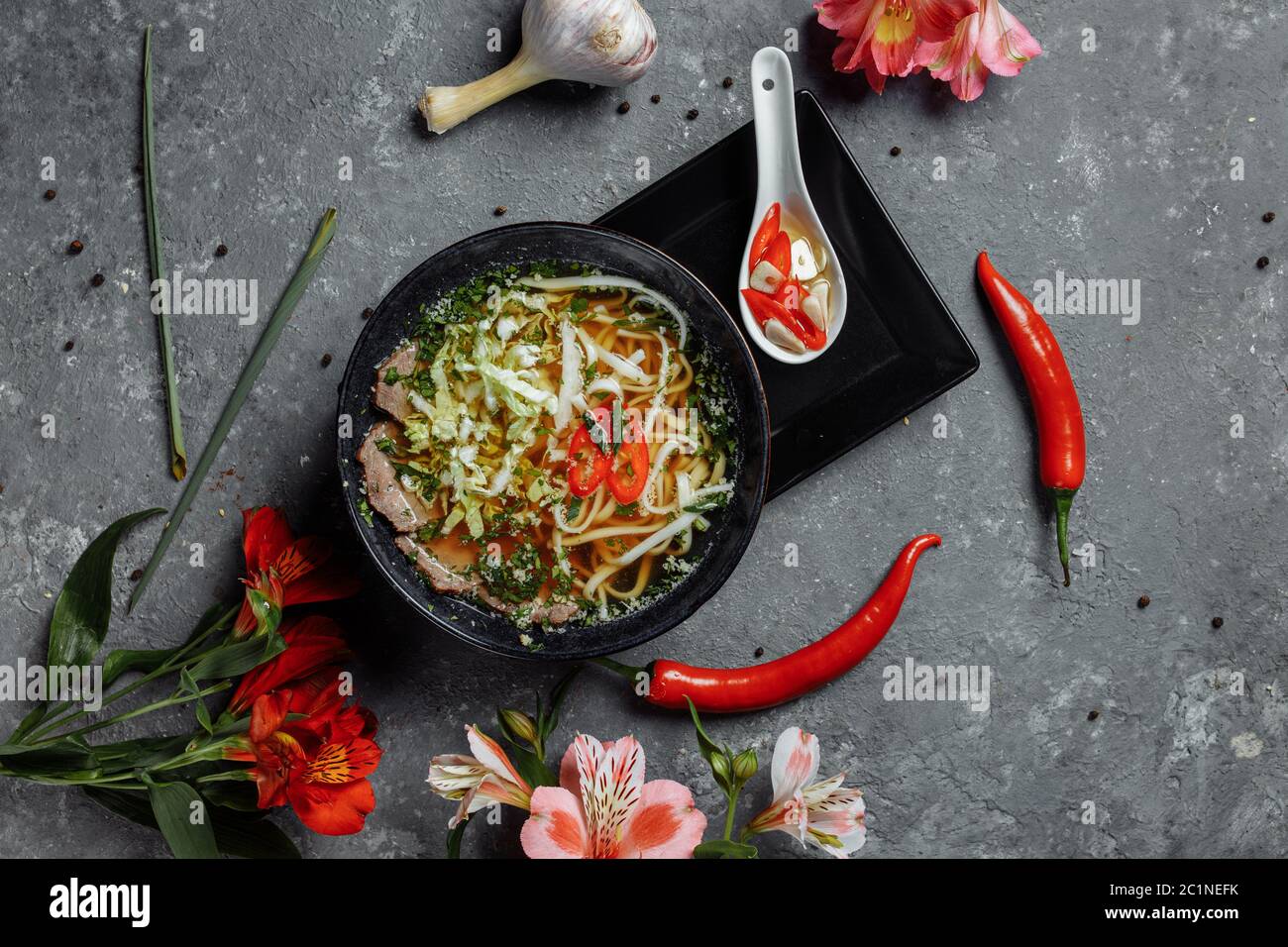 Asian cuisine, Beef soup fo in a black plate on a dark background. Soup Fo with Spicy beef broth, beef tenderloin, udon noodles, chili paste Stock Photo