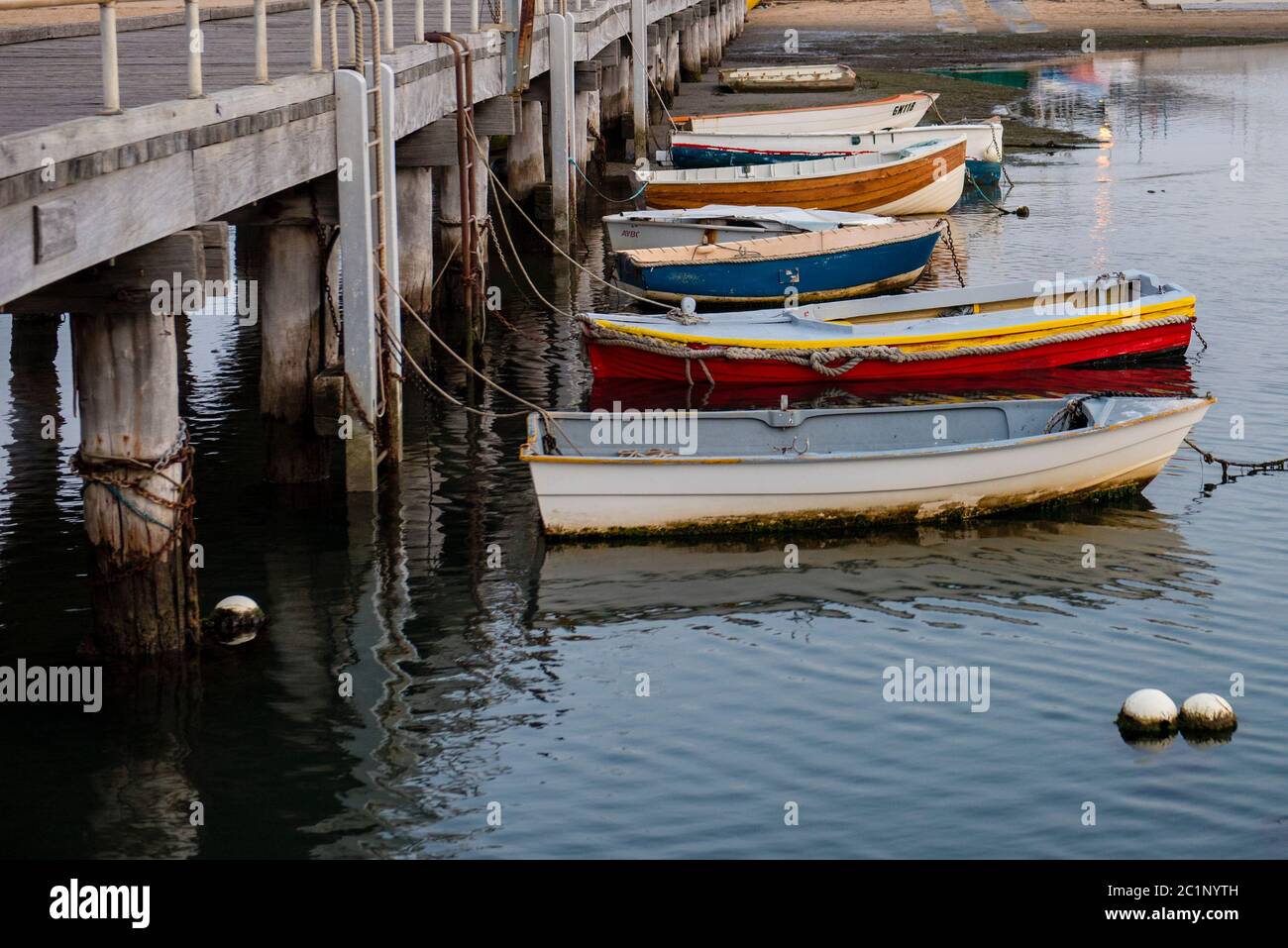 Row of old small fishing boats tied up to jetty, Victoria Australia Stock Photo