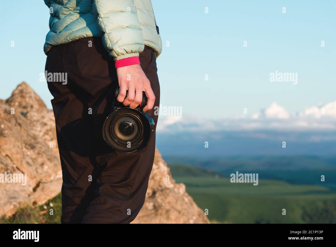 Close-up DSLR camera in the hands of the girl photographer in nature with a camera in hand. Side view Stock Photo