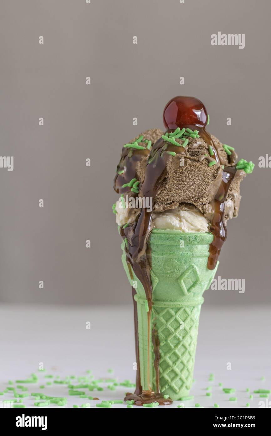 Icecream cone with green wafer and chocolate ice cream with cherry on top Stock Photo