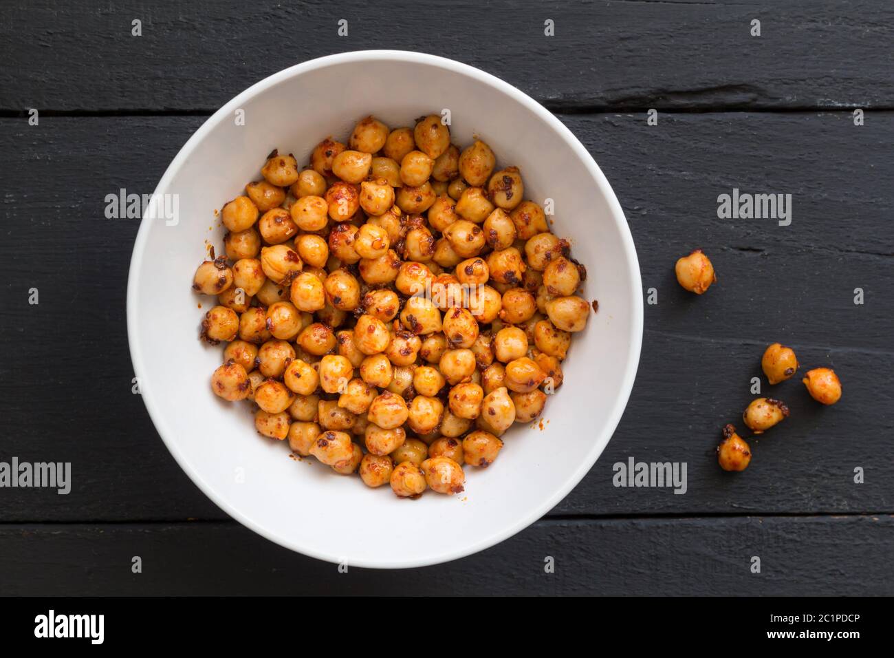 Chickpeas with olive oil and chili flakes - Spicy chickpeas in white bowl on black rustic background Stock Photo