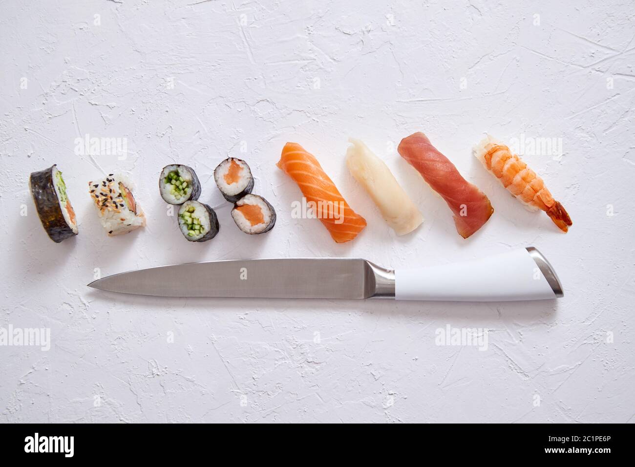 Various sushi rolls with Japanese knife on white stone slate background Stock Photo