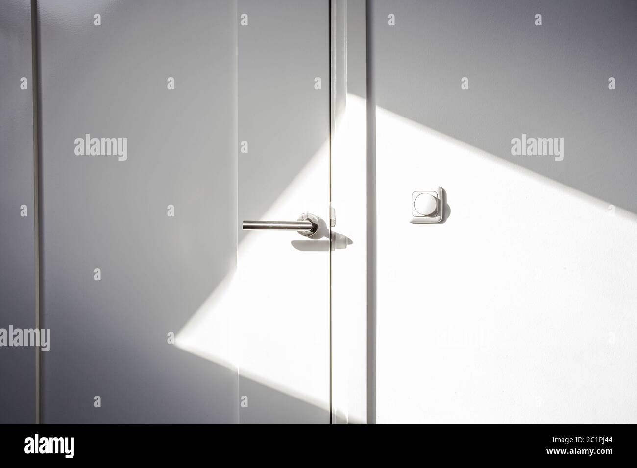 Close-up white door with sunlight. Chrome door ,The light switch on the wall modern design empty and clean Stock Photo