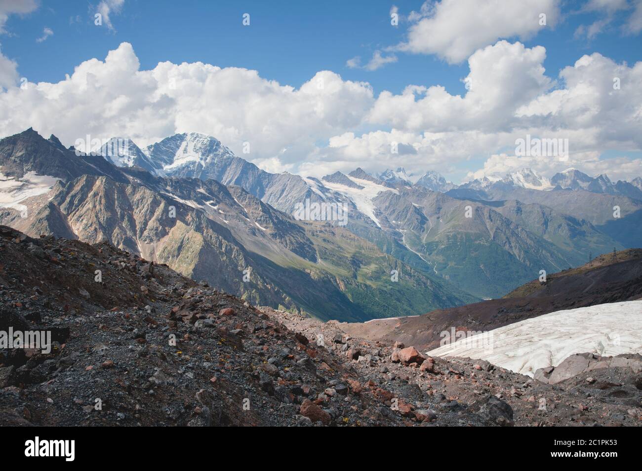 Mountain landscape dusty dirty volcanic slope with a cracked melting glacier against the backdrop of the Caucasus Mountains. Glo Stock Photo