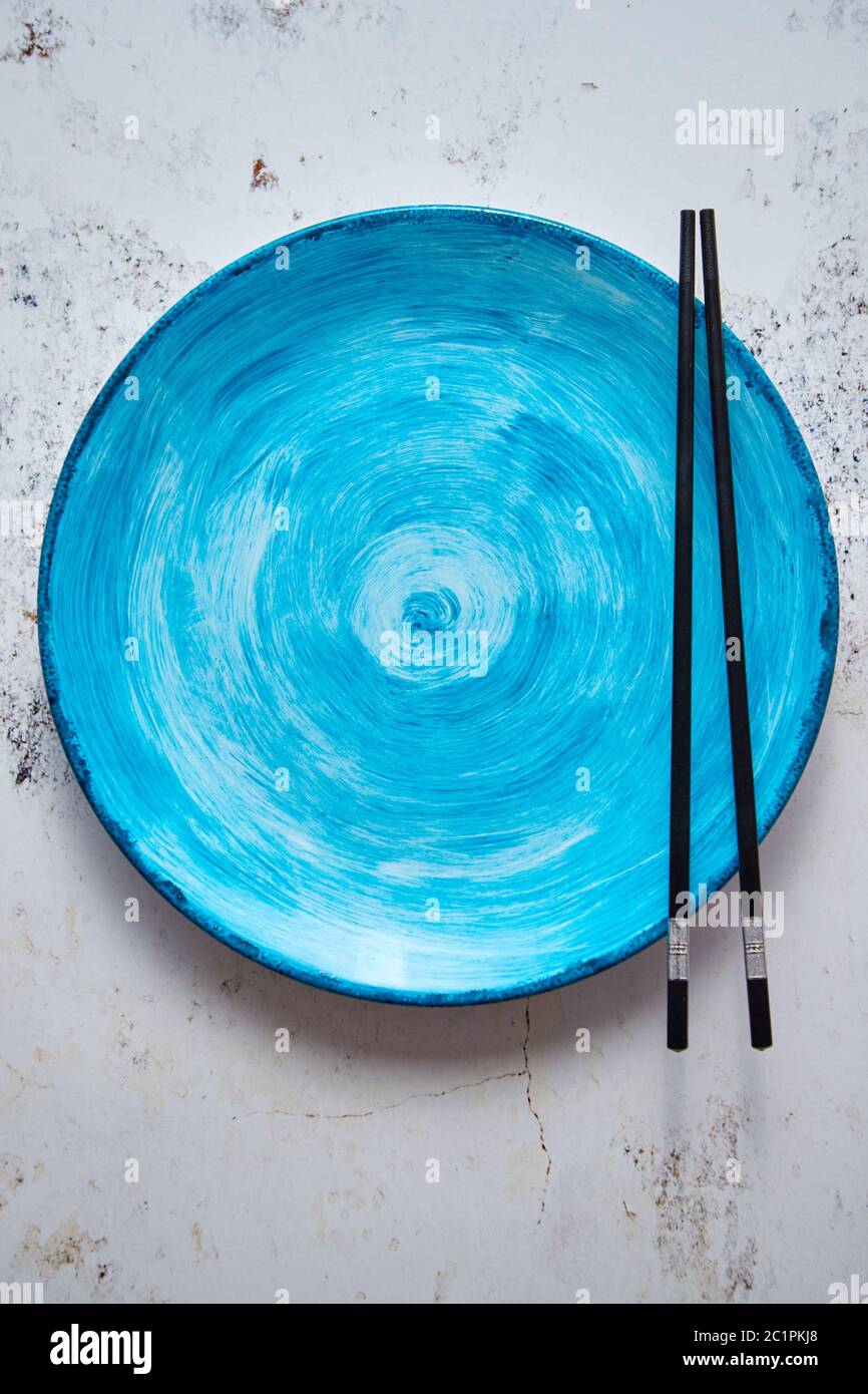 Turquoise hand painted ceramic serving plate with wooden chopsticks on side Stock Photo