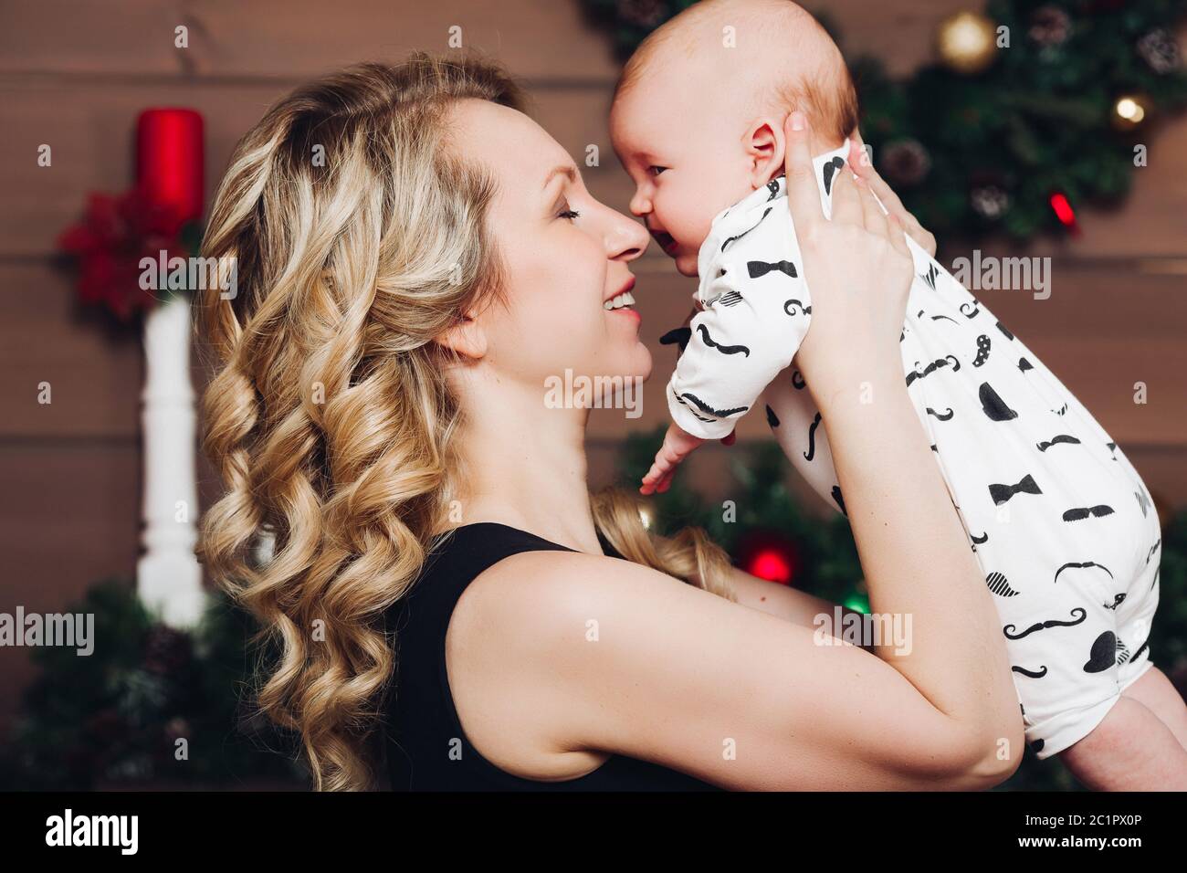 Boy with beautiful blonde mom embracing in decorated studio for Christmas. Stock Photo