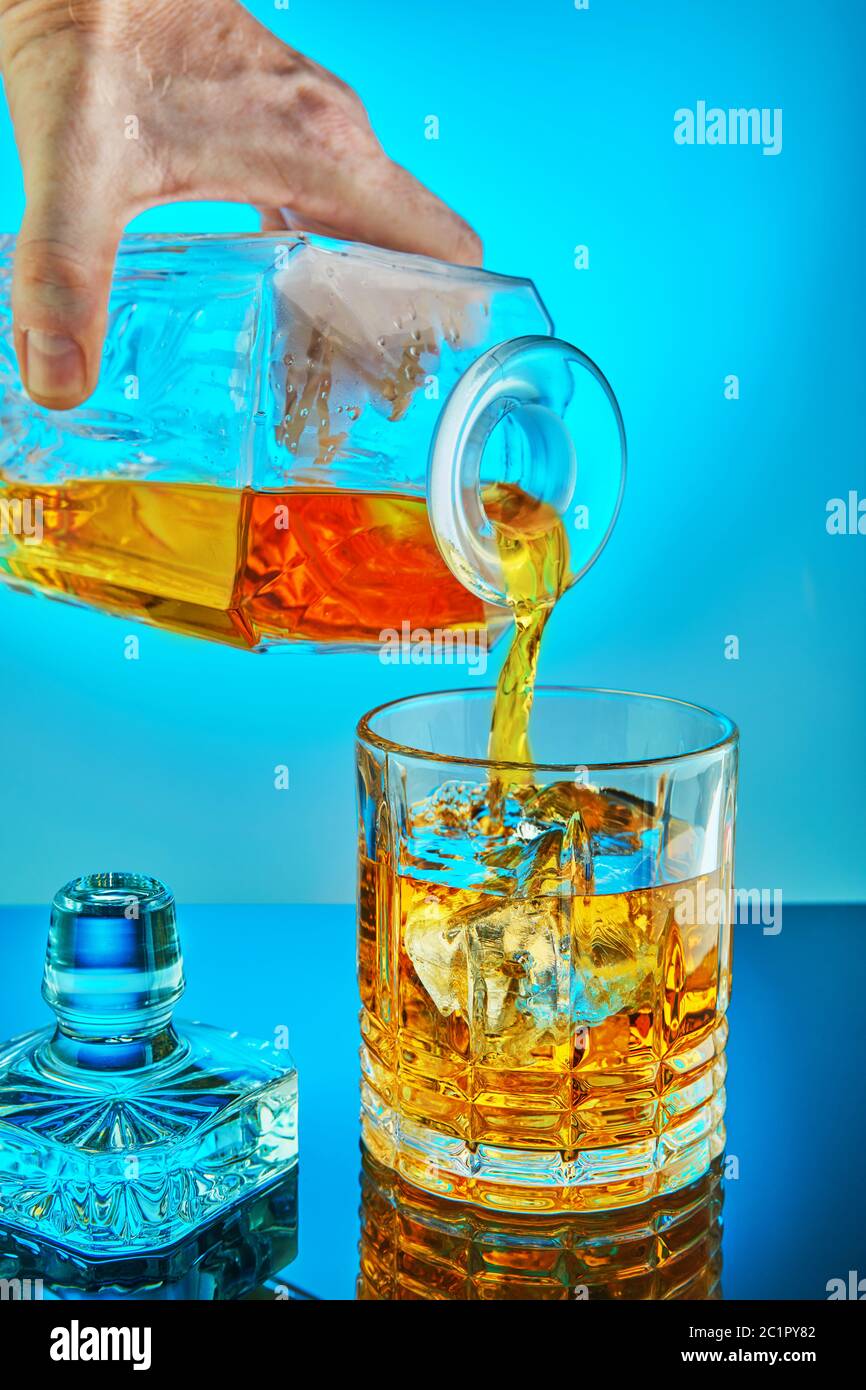 Pouring square crystal decanter with scotch tape whiskey or brandy in a