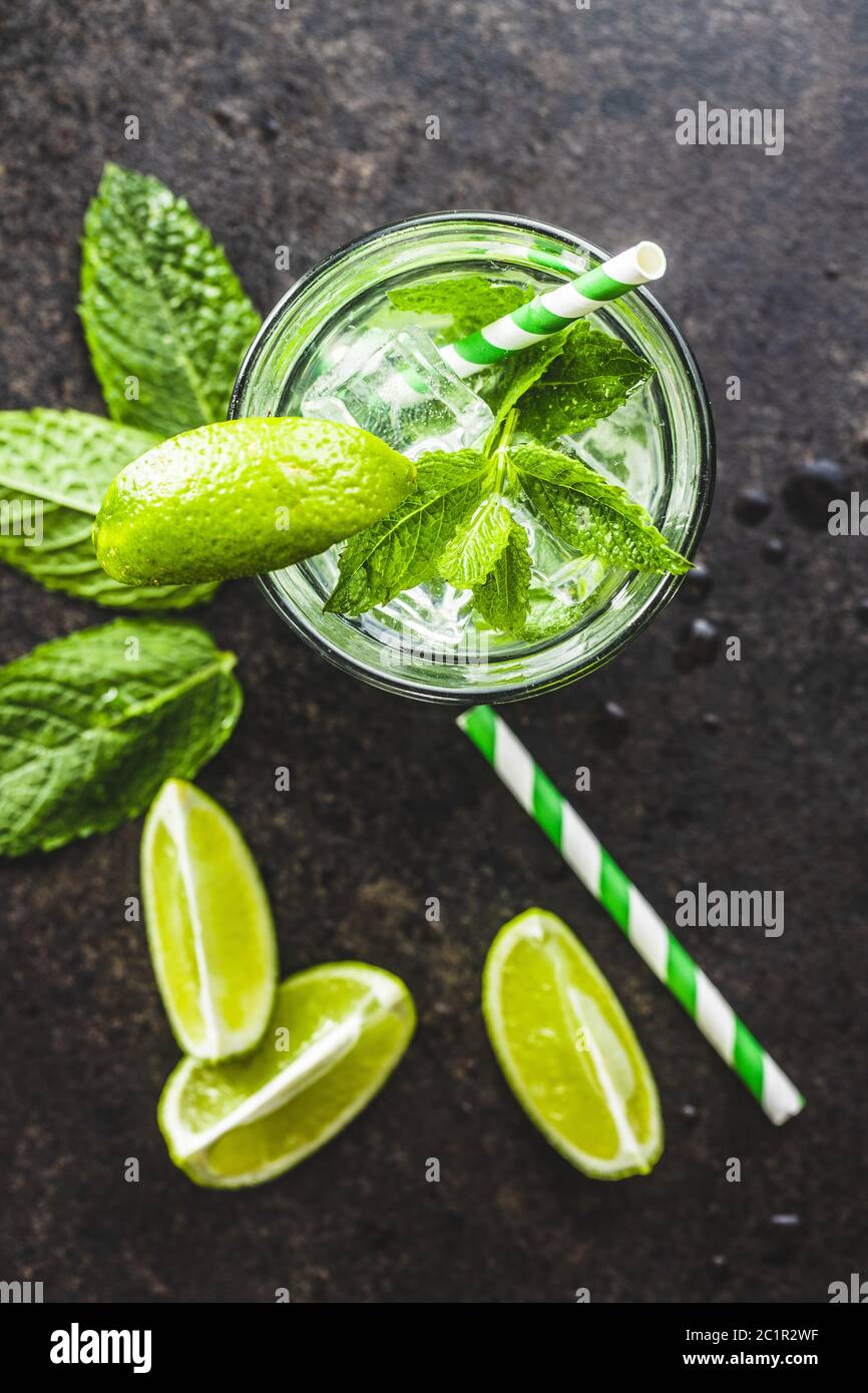 Cocktail with lime, mint and ice cubes on black table. Top view. Stock Photo