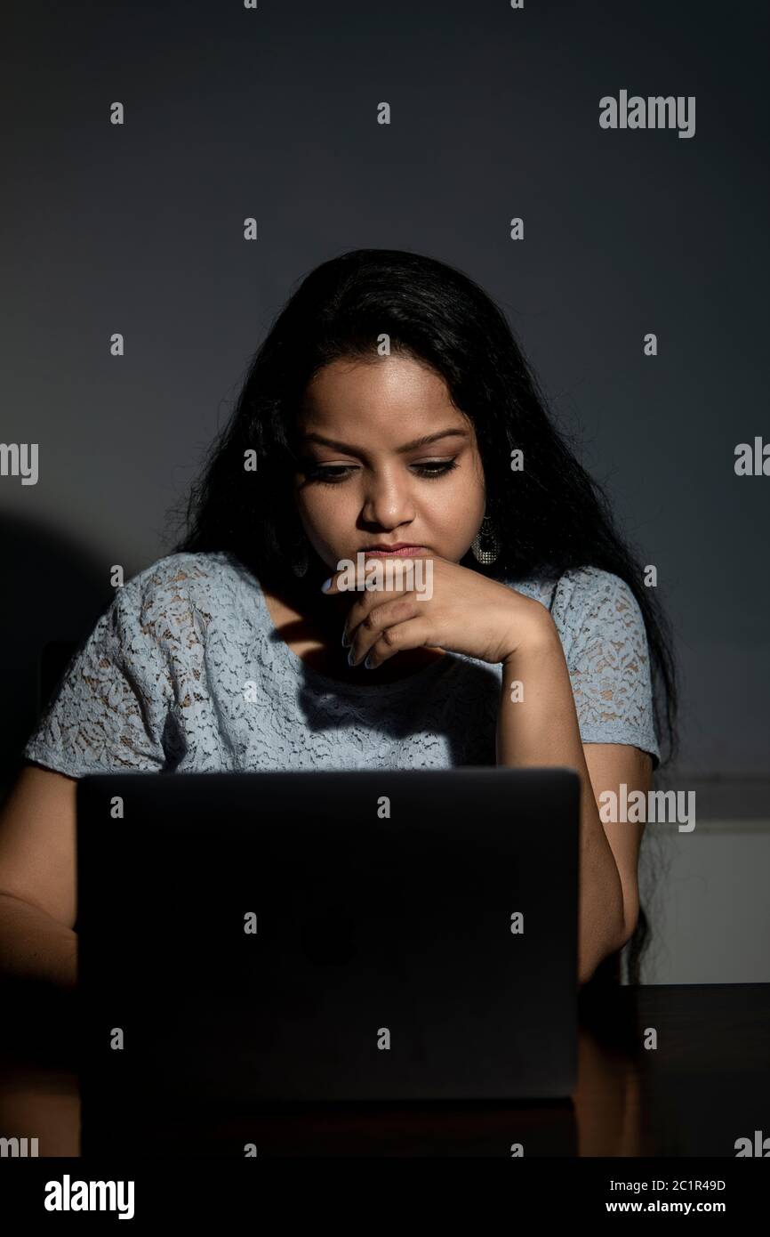 An Indian lady working late at night on her computer Stock Photo