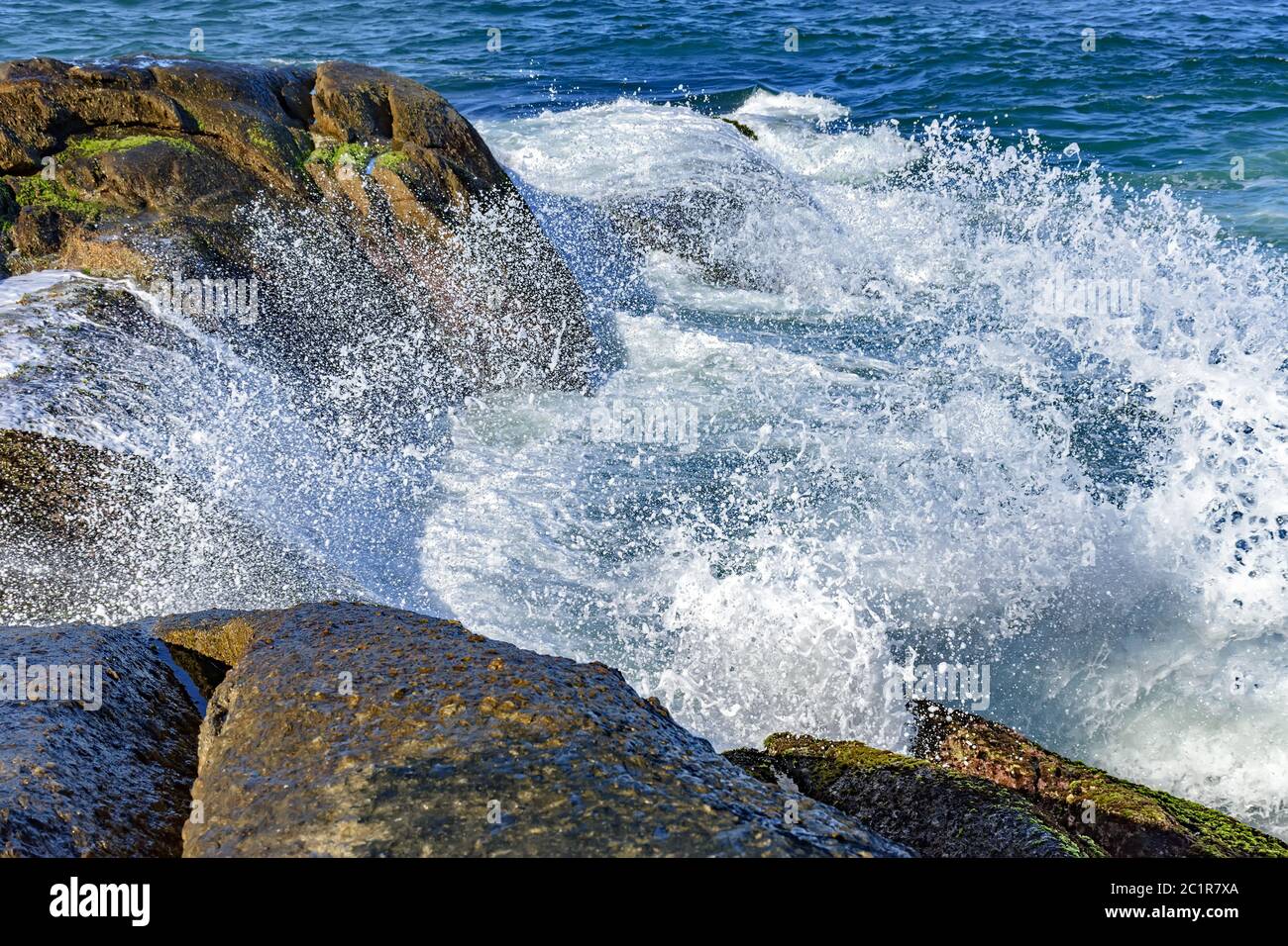 Waves crashing over rocks with water drops Stock Photo