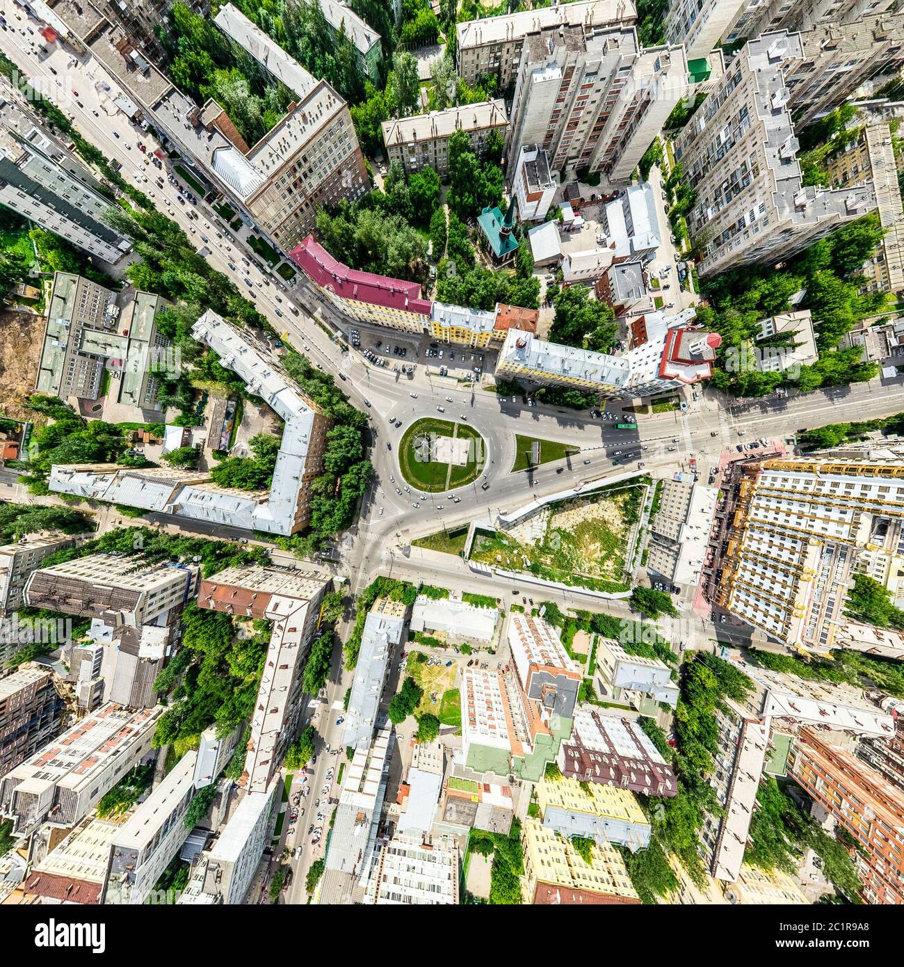 Aerial city view with crossroads and roads, houses, buildings, parks and parking lots. Sunny summer panoramic image Stock Photo