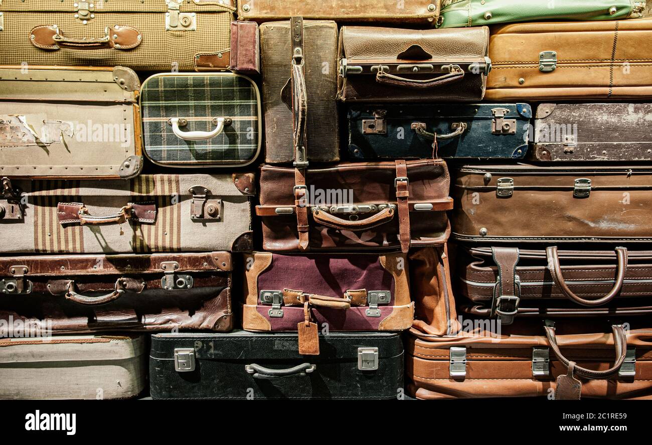 Stack of old assorted styles leather and fabric luggages. Vintage baggages background Stock Photo