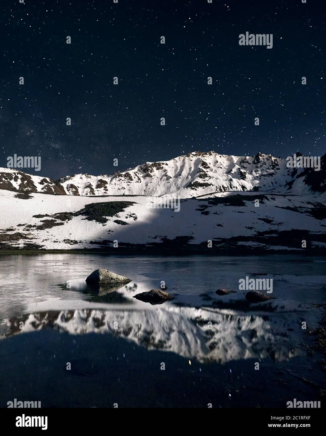 Beautiful scenery of white peak mountains and lake at foreground against night sky full of stars. Astrophotography and long exposure. Stock Photo