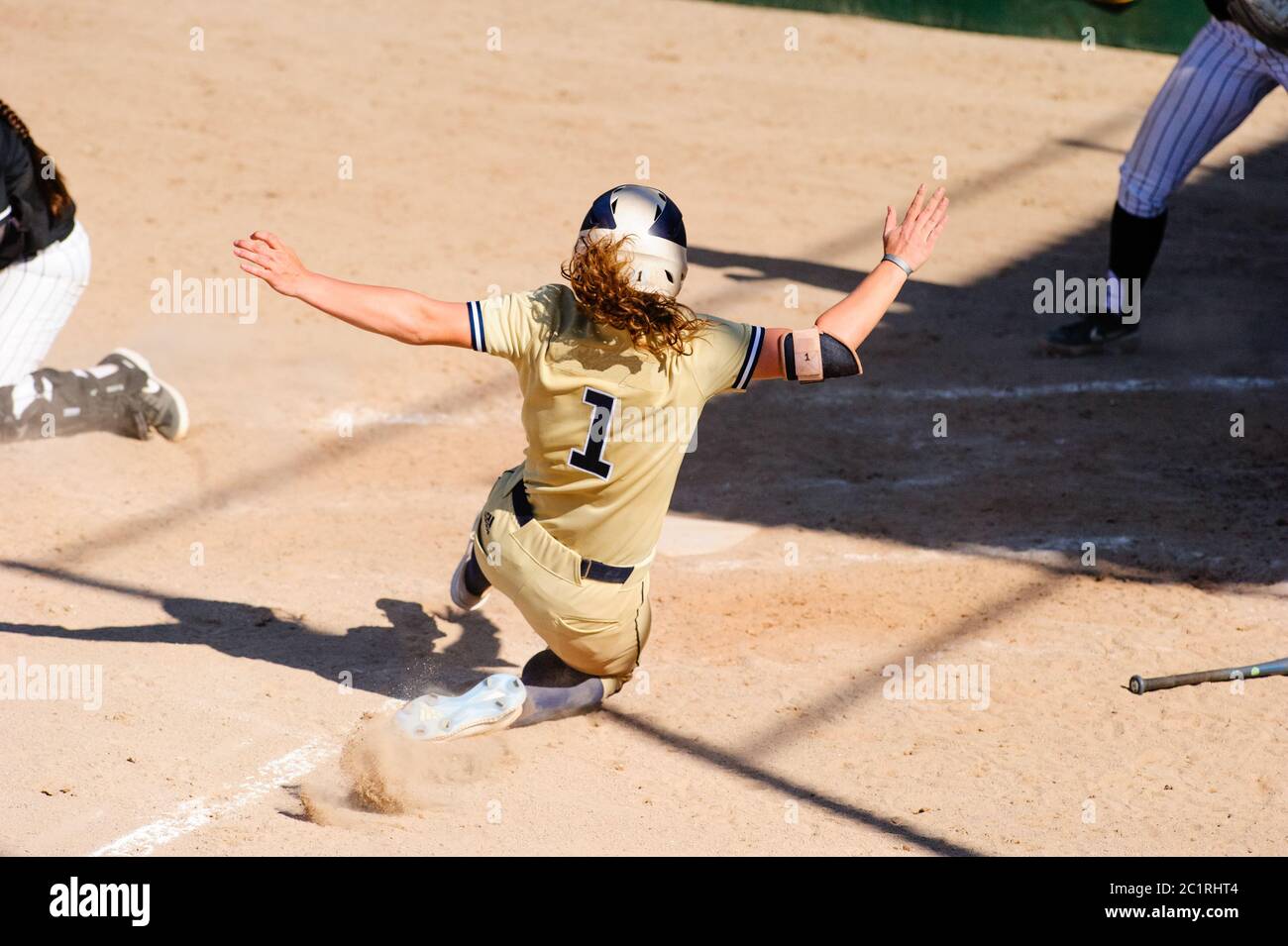 A Baseball Player is Sliding at Home Plate Stock Photo