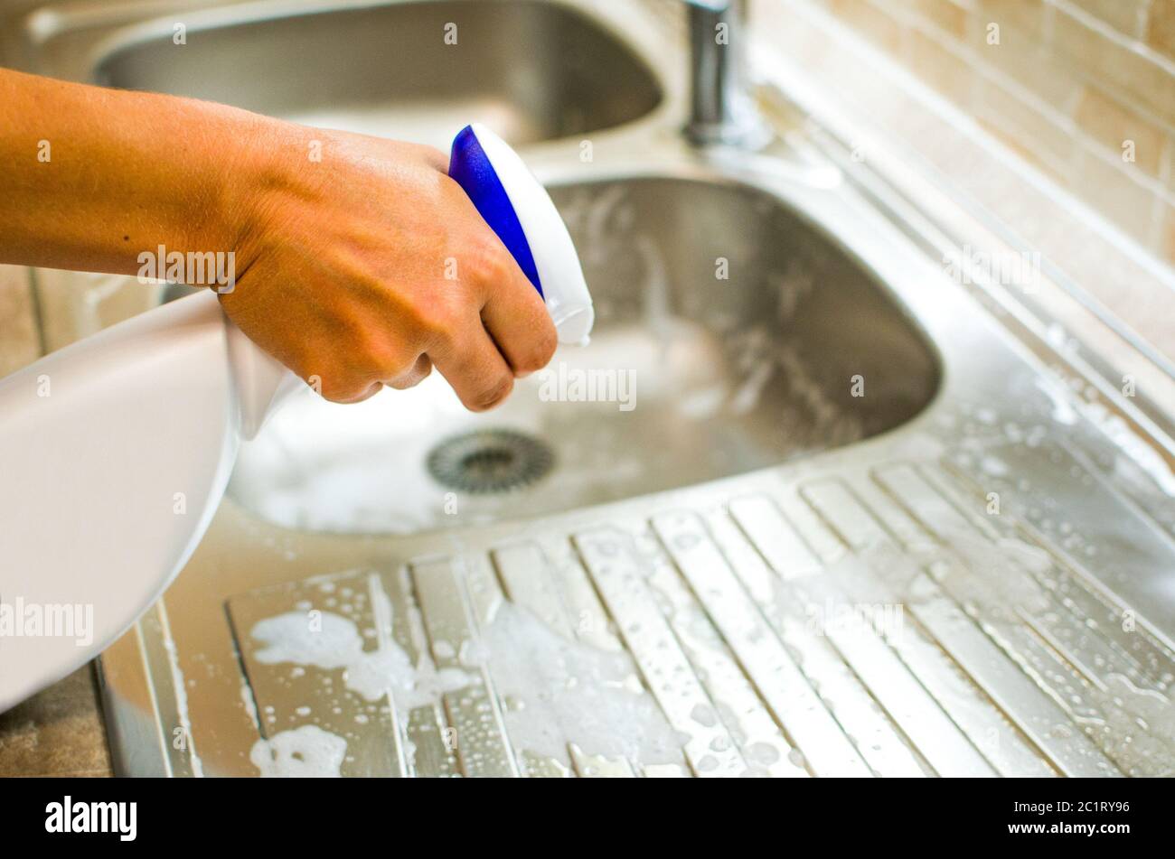 Woman doing chores in the kitchen at home , sink and faucet with spray cleaner Stock Photo